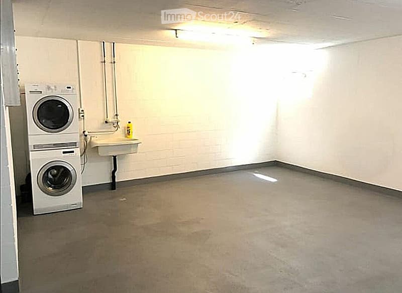 Laundry room with a stacked washing machine and dryer, a small sink, and a bottle of cleaning supplies on the counter.