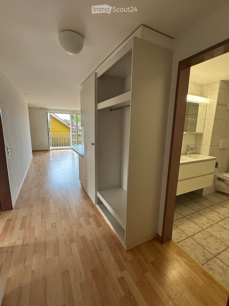 Empty hallway with wooden flooring, built-in closet, and access to a balcony.