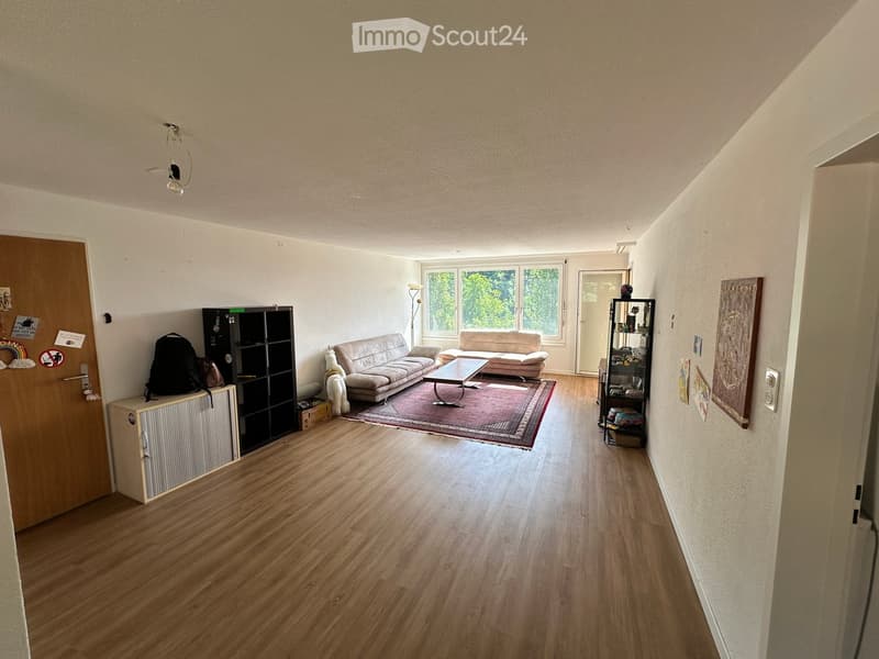 Living room with light wooden flooring, two sofas, a coffee table, shelves, and artwork on the walls.