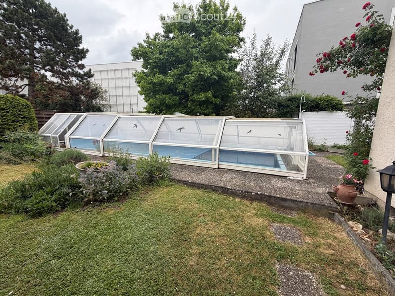 Garden with a greenhouse, lawn, potted plants, and a pathway.