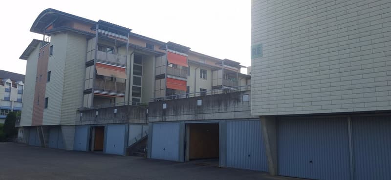 Multi-story residential building with balconies, garage, and modern facade.