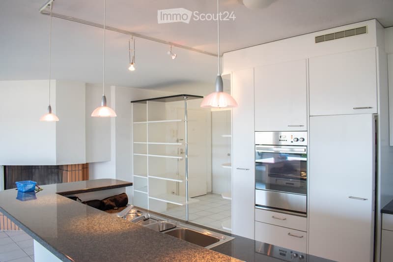 Modern kitchen with white cabinets, stainless steel oven, granite countertop, and pendant lights.