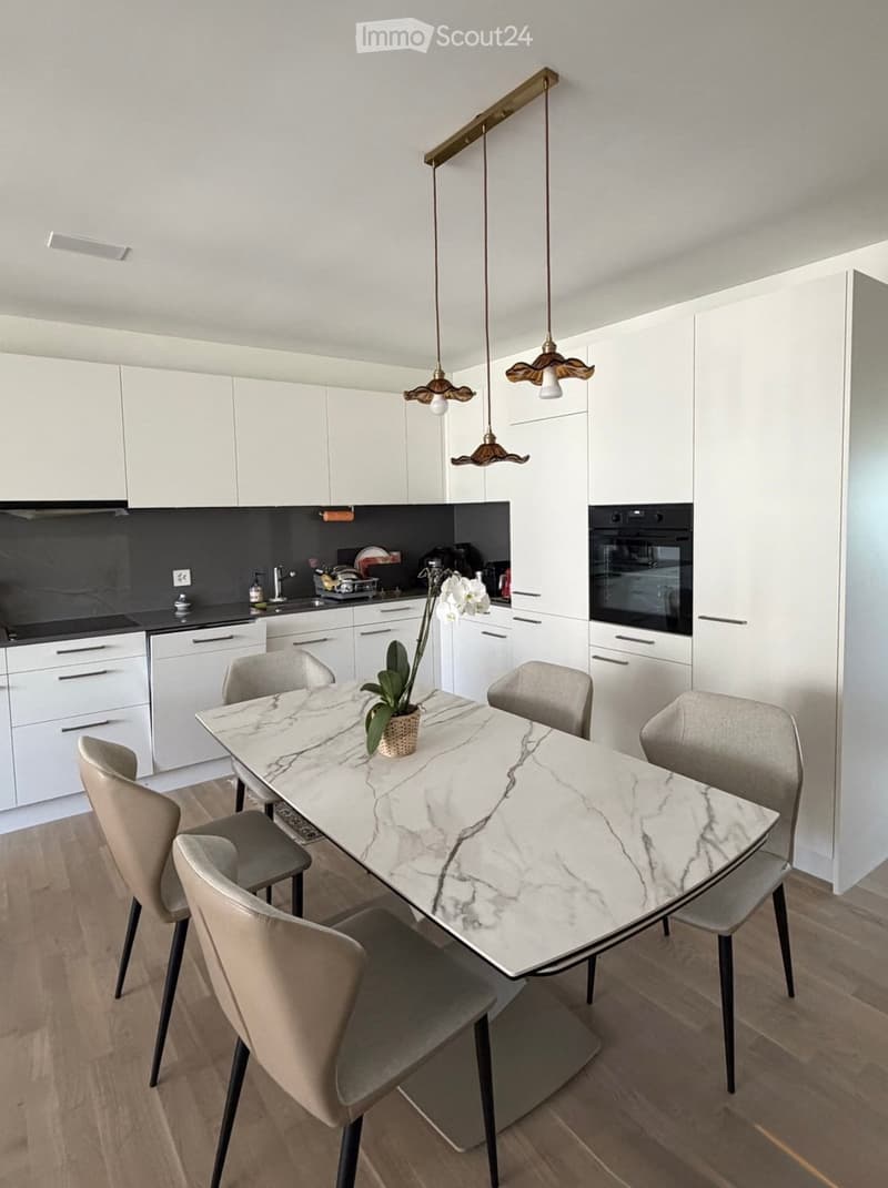 Modern kitchen with white cabinets, a marble dining table, six chairs, and pendant lights.