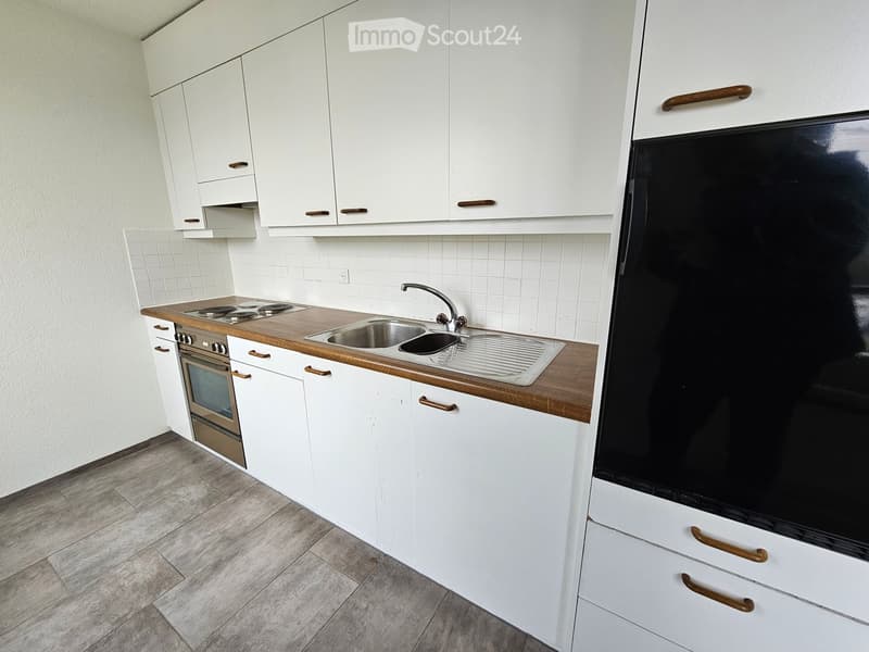 Modern kitchen with white cabinets, wooden countertops, stainless steel sink, and built-in oven and refrigerator.