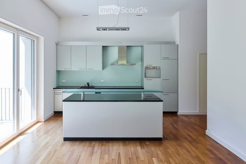 Modern kitchen with white cabinets, a central island, and a glass countertop. Features include a built-in oven, a range hood, and a sink.