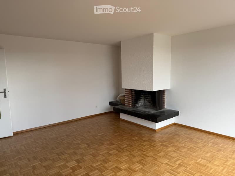 Empty room with wooden flooring, white walls, and a fireplace with a black surround and white mantle.
