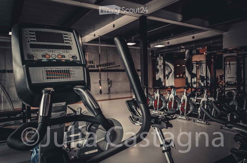 Modern gym with elliptical machine and stationary bikes, digital display, sleek design, clean and organized space.