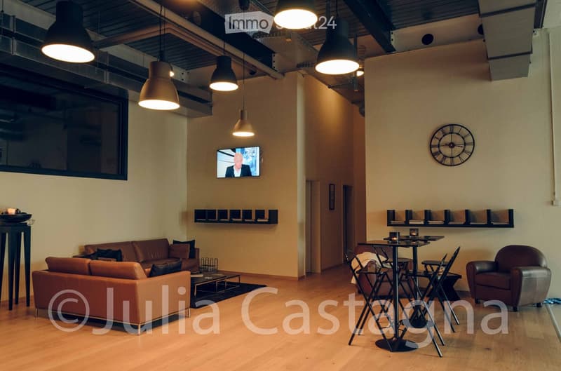 Modern living room with a brown leather sofa, coffee table, armchair, small table with chairs, television, and wall-mounted shelves.