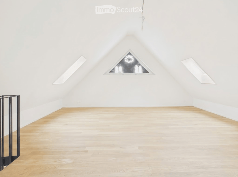 Completely empty room with white walls, wooden floor, and skylight windows.