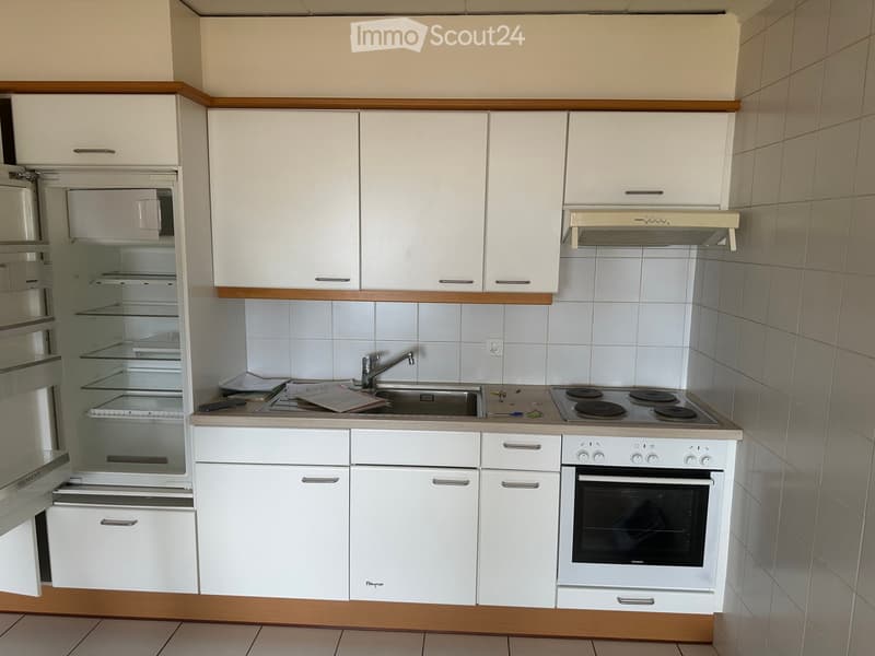 Compact kitchen with white cabinets, a refrigerator, stove, oven, and sink. Wooden trim accents the cabinetry.