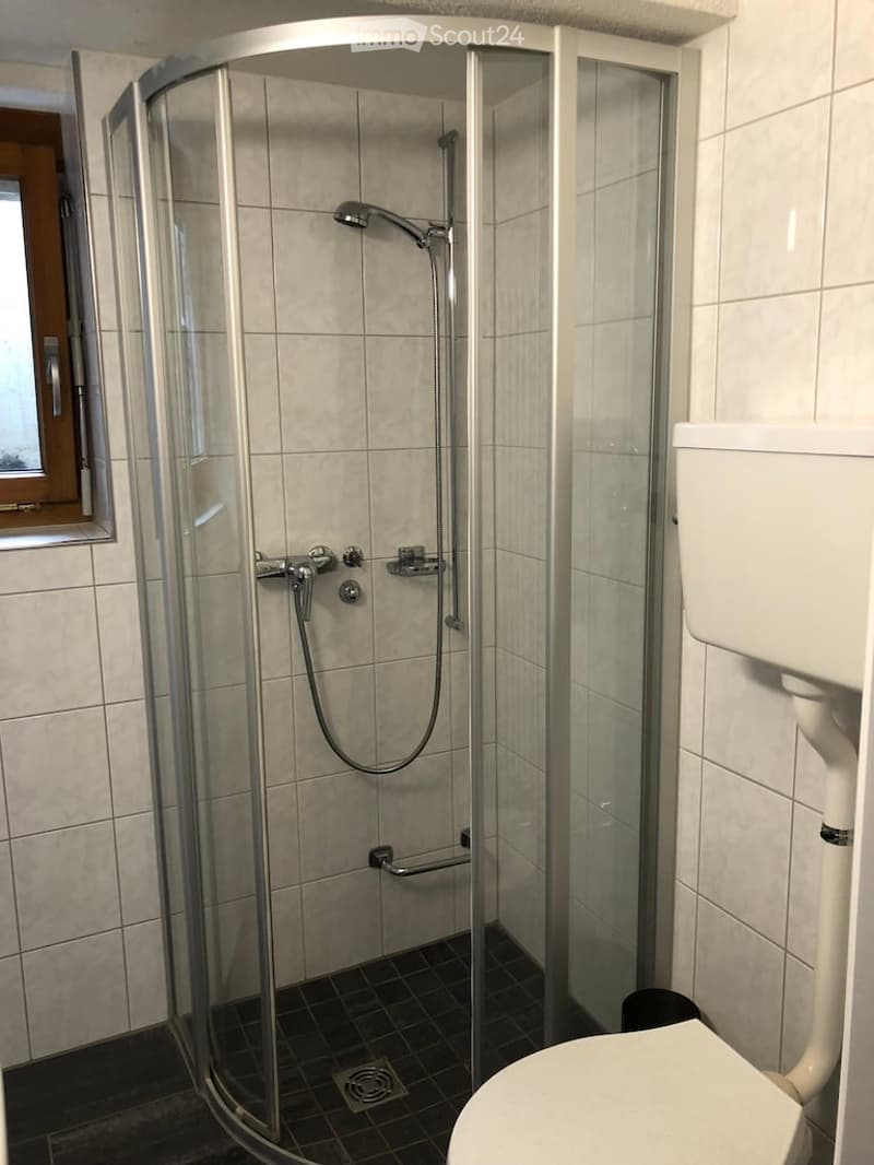 white toilet, white tiles, glass shower stall, shower head, tiled floor, shower wall fixtures, waste water disposal