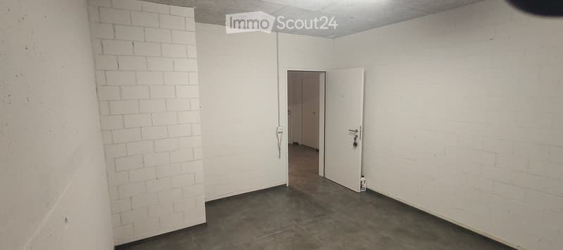 Empty room with white brick walls, concrete floor, and two open doors leading to adjacent spaces.