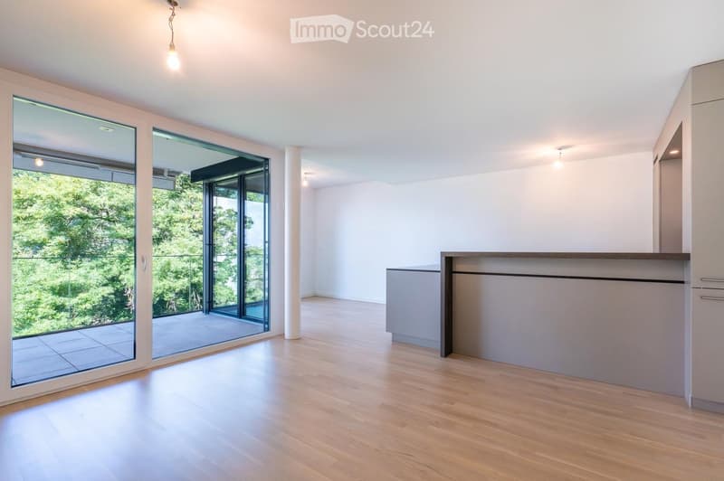 Bright, unfurnished room with large glass doors leading to a balcony, light wooden flooring, and modern built-in cabinetry.