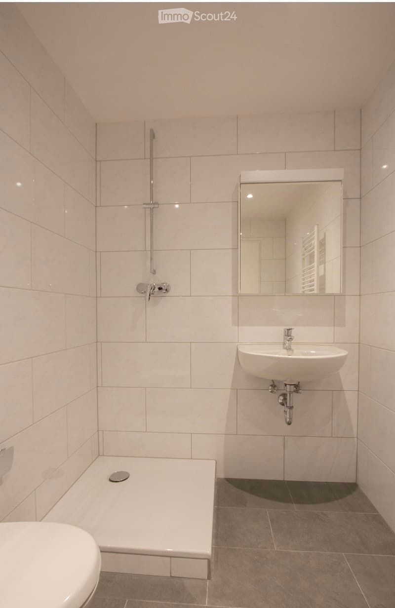 Modern bathroom with a white bathtub, a sink with a mirror, and a shower area with a glass enclosure.