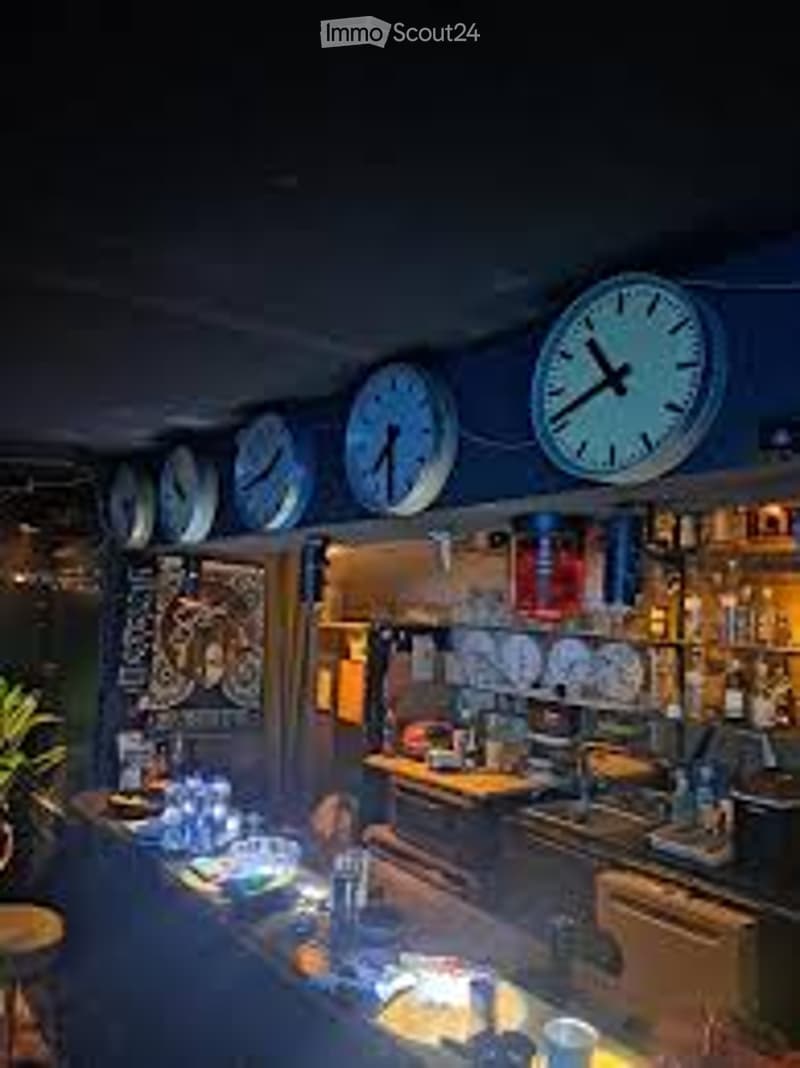 A cozy kitchen with multiple clocks on the wall, a counter with cups and bottles, and a sink with a faucet.