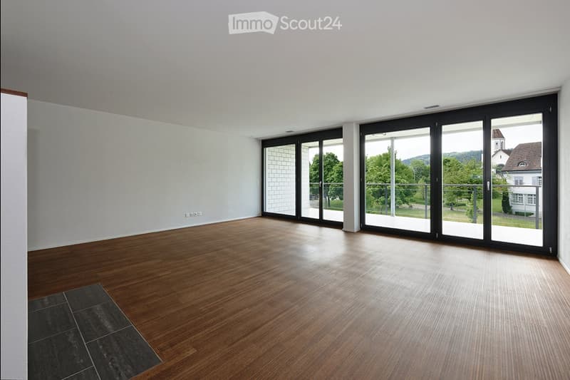 Empty room with wooden flooring, white walls, and large sliding glass doors leading to a balcony or outdoor area.