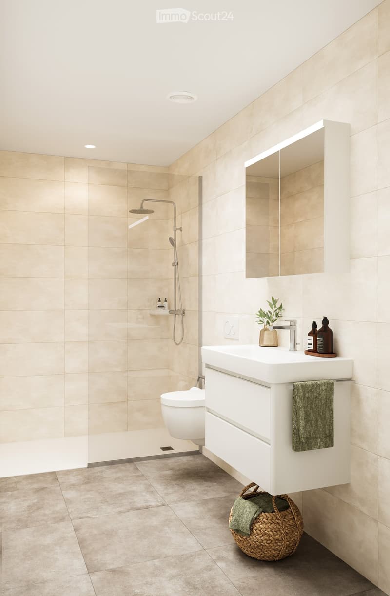 Modern bathroom with beige tiles, white sink, mirror, toilet, and shower area. Includes a woven basket with towels and a small plant on the sink.