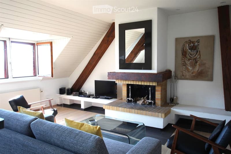 Modern living room with a fireplace, large windows, a sofa, chairs, a coffee table, a TV, and a painting on the wall.