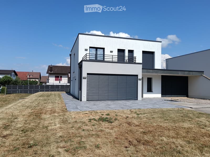 Modern two-story house with white exterior, garage, balcony, and contemporary design.