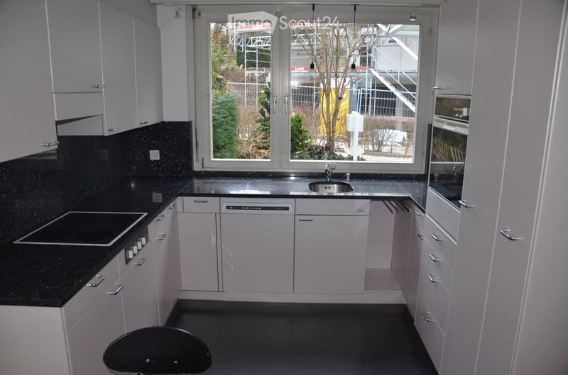 Modern kitchen with white cabinets, black countertops, and stainless steel appliances, including an oven, dishwasher, and sink.