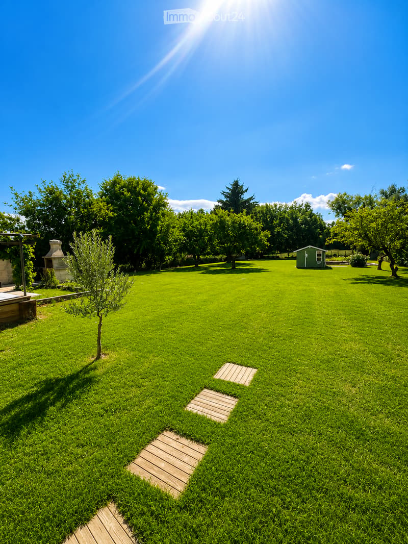 A well-maintained garden with a lush green lawn, scattered trees, a small shed, and wooden stepping stones leading through the grass.