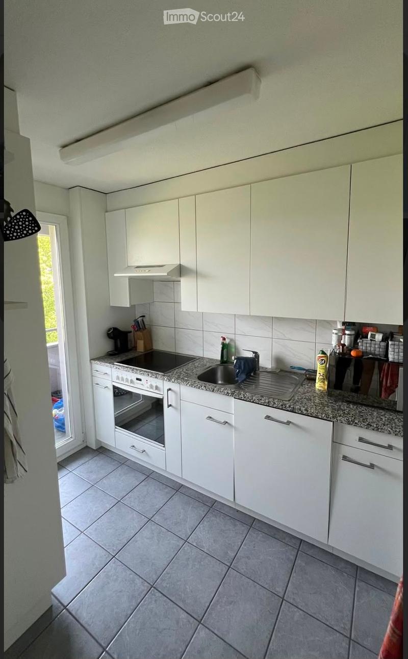 Modern kitchen with white cabinets, granite countertop, built-in oven, and stainless steel sink.