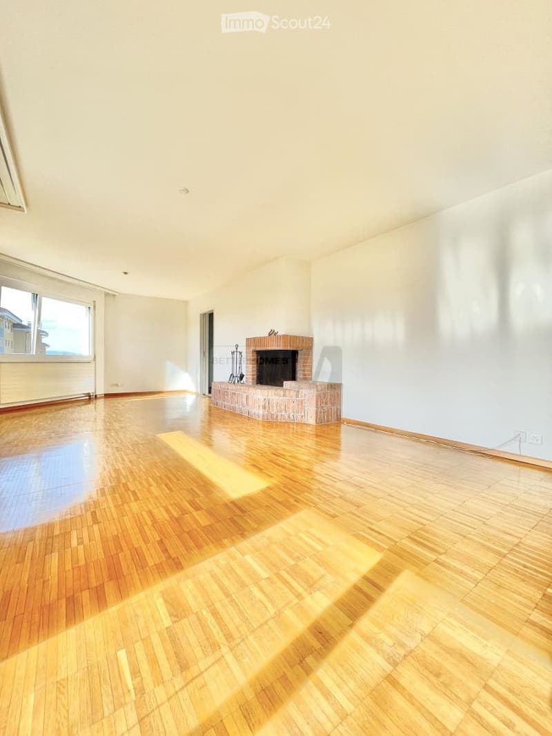 Empty room with wooden flooring, white walls, and a brick fireplace. No furniture or equipment present.