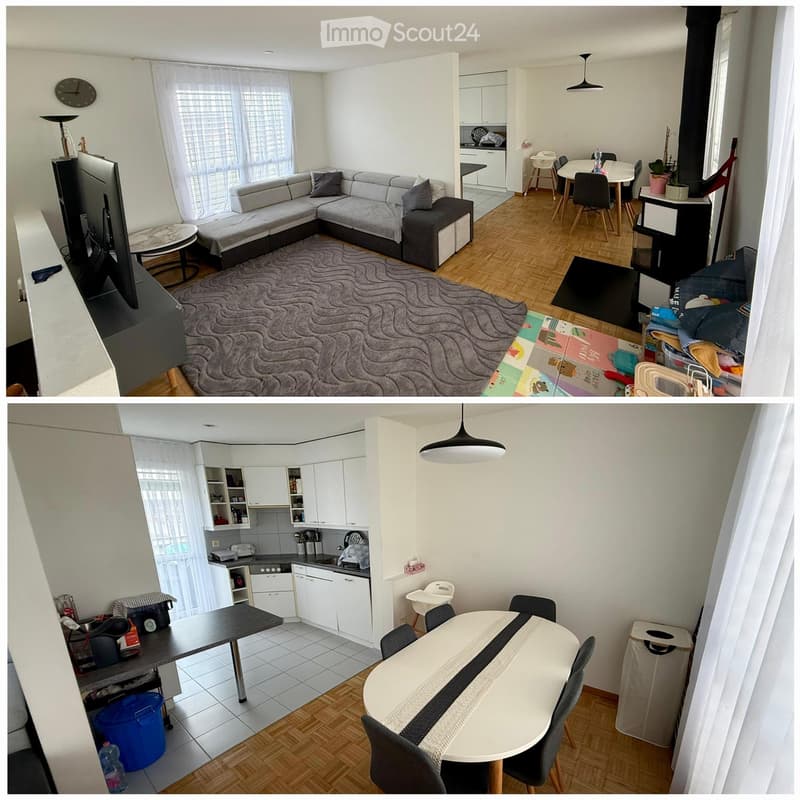 Modern furnished living and dining area with a grey sectional sofa, coffee table, dining table with chairs, kitchen area with cabinets and appliances, and a lamp.