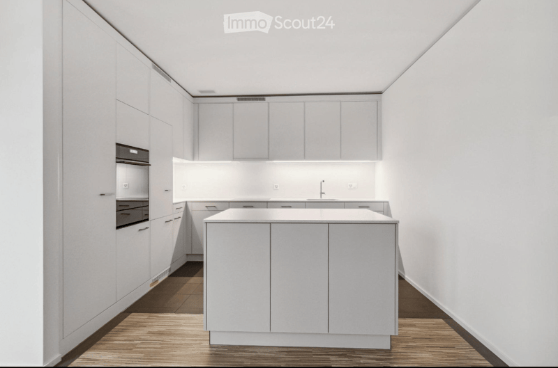 Modern, minimalist kitchen with white cabinets, a central island, and a sleek design. Features include a built-in oven, a sink with a modern faucet, and ample storage space.