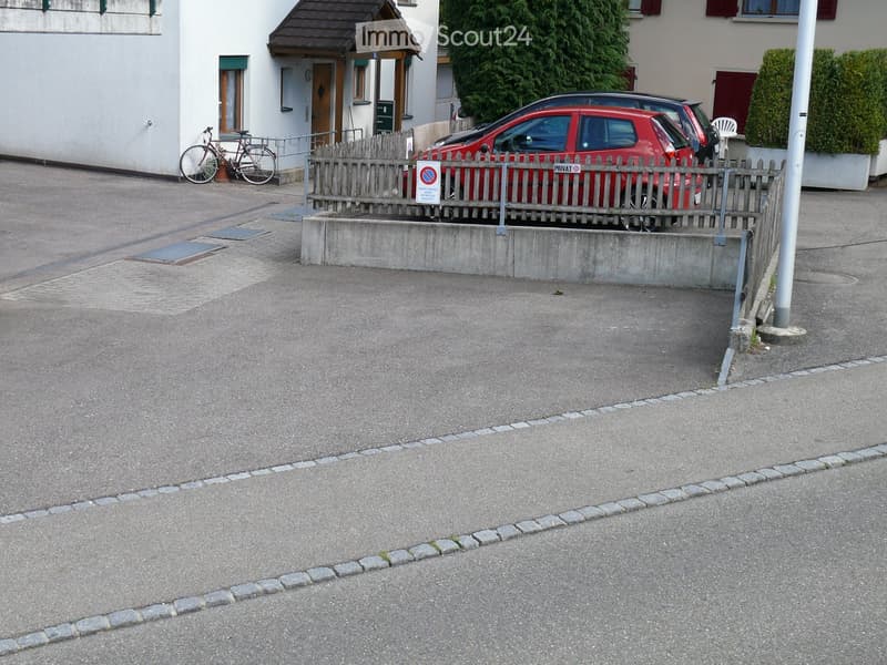 {"type": "Parking place", "objects": [], "description": "Parking area with a red car, bicycle, and a small wooden fence separating it from the street.", "localized_descriptions": {"EN": "Parking area with a red car, bicycle, and a small wooden fence separ