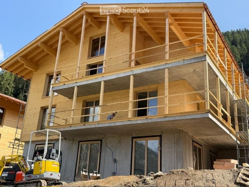 Wooden two-story building under construction with exposed beams, large windows, and a balcony on the upper level.