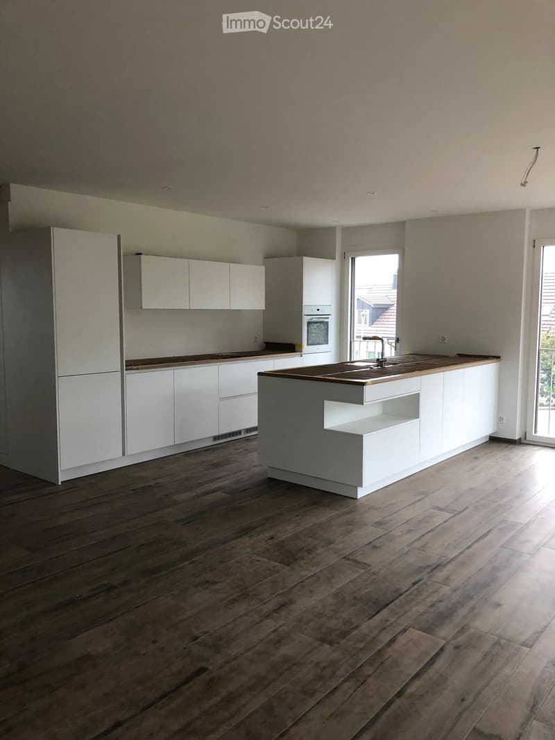 Modern kitchen with white cabinets, a central island, and wooden countertops, featuring a sink and faucet.