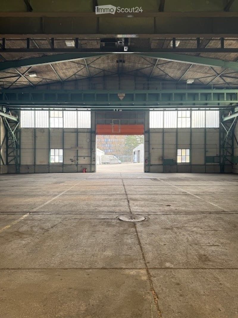 Industrial building with large doors and windows, concrete floor, metal beams, empty
