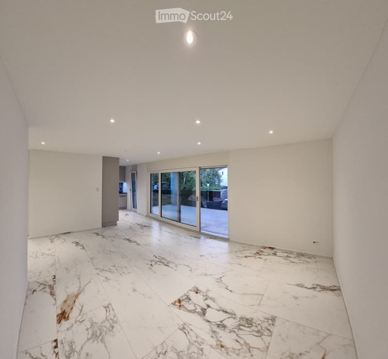 Empty room with white marble flooring, white walls, recessed lighting, and large glass sliding doors leading outside.