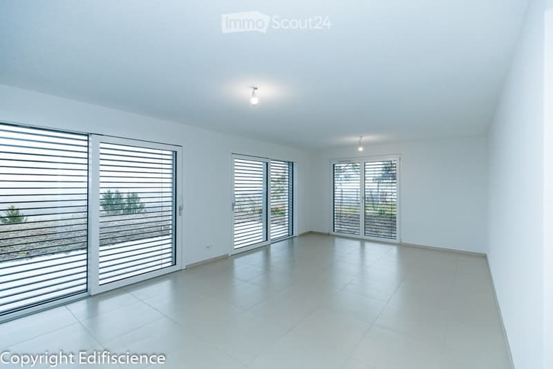 Completely empty room with white walls, tiled floor, and large sliding glass doors leading to an outdoor area.