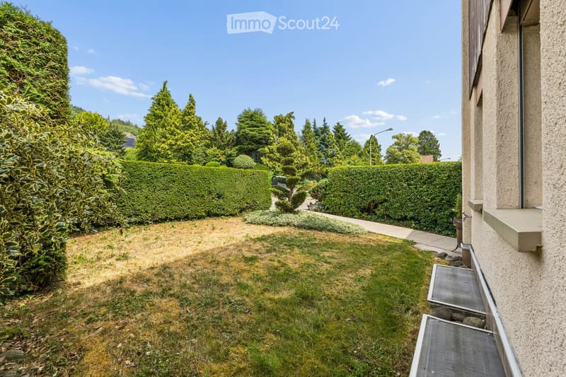 Well-maintained garden with neatly trimmed hedges, a small lawn, and a pathway leading to the house.