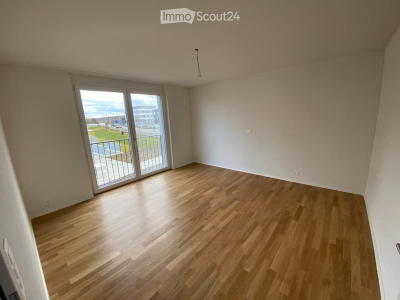 Empty room with wooden flooring, white walls, and large sliding glass doors leading to a balcony.