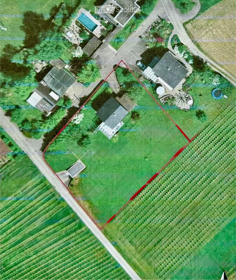 Aerial view of a residential property with multiple buildings, including a main house, outbuildings, and a swimming pool, surrounded by green fields and a road.
