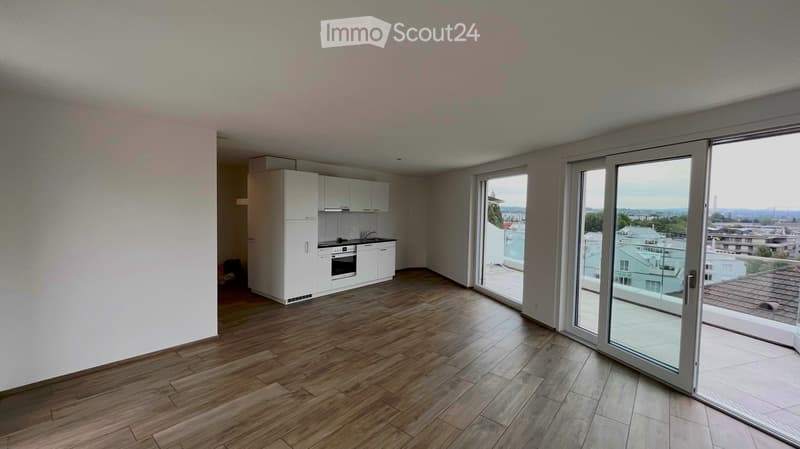 Modern kitchen with white cabinets, wooden flooring, and large sliding glass doors leading to a balcony with a city view.