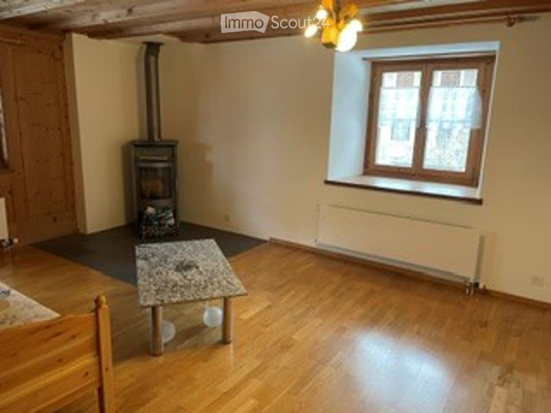 Wooden floor, fireplace, small table, and stool in a cozy room.