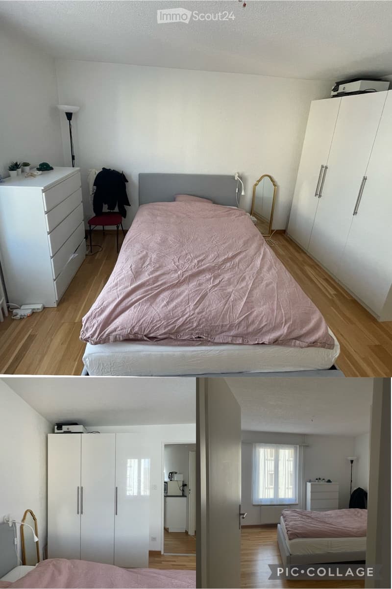 Cozy bedroom with a wooden floor, a grey bed with pink bedding, a white wardrobe, a small mirror, a red stool, a floor lamp, and a small plant on a dresser.