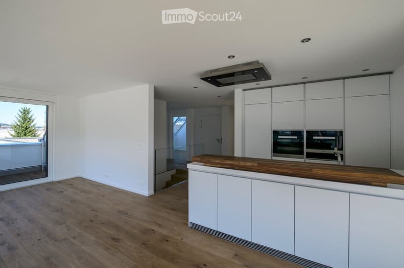 Modern kitchen with white cabinets, wooden countertop, and built-in oven. Large window offers a view of the outdoor area.