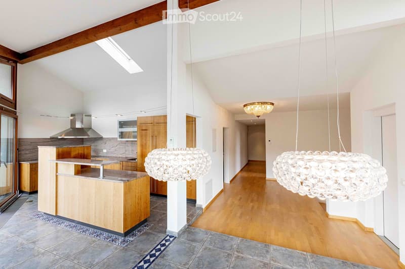 Modern kitchen with wooden cabinets, stainless steel range hood, central island, and large pendant lights.