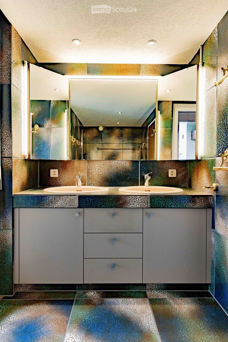 Modern bathroom with two sinks, mirrored cabinet, colorful mosaic tiles, and sleek grey cabinets.