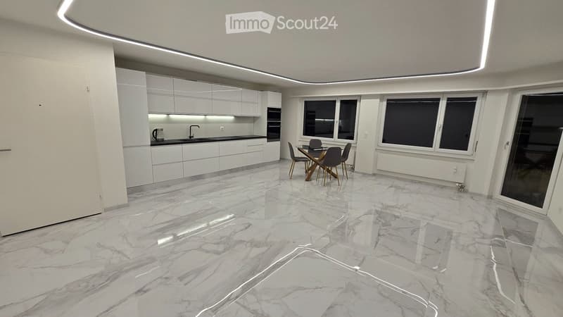 Modern kitchen and dining area with white cabinets, marble flooring, and large windows. Includes a sink, faucet, oven, and a dining table with chairs.
