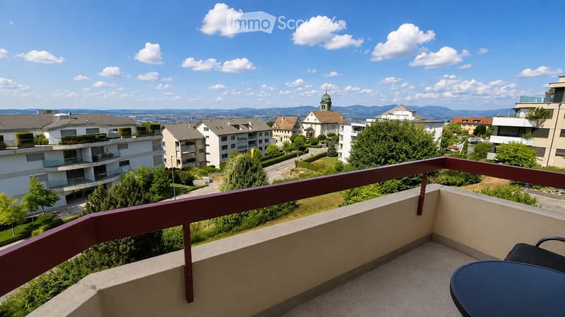 Balcony with a view of a residential area, featuring a table and a chair.