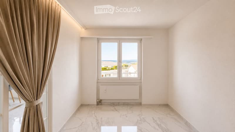 Empty room with marble flooring, white walls, large window with view, and beige curtains.