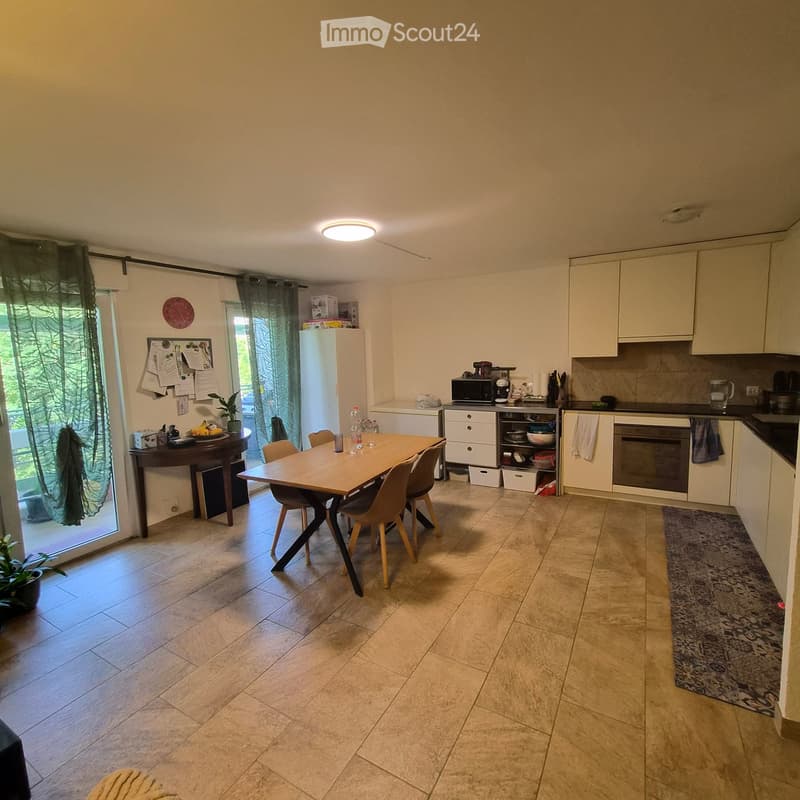 Bright kitchen with tiled floor, white cabinets, a dining table with chairs, a refrigerator, microwave, and various kitchen appliances.