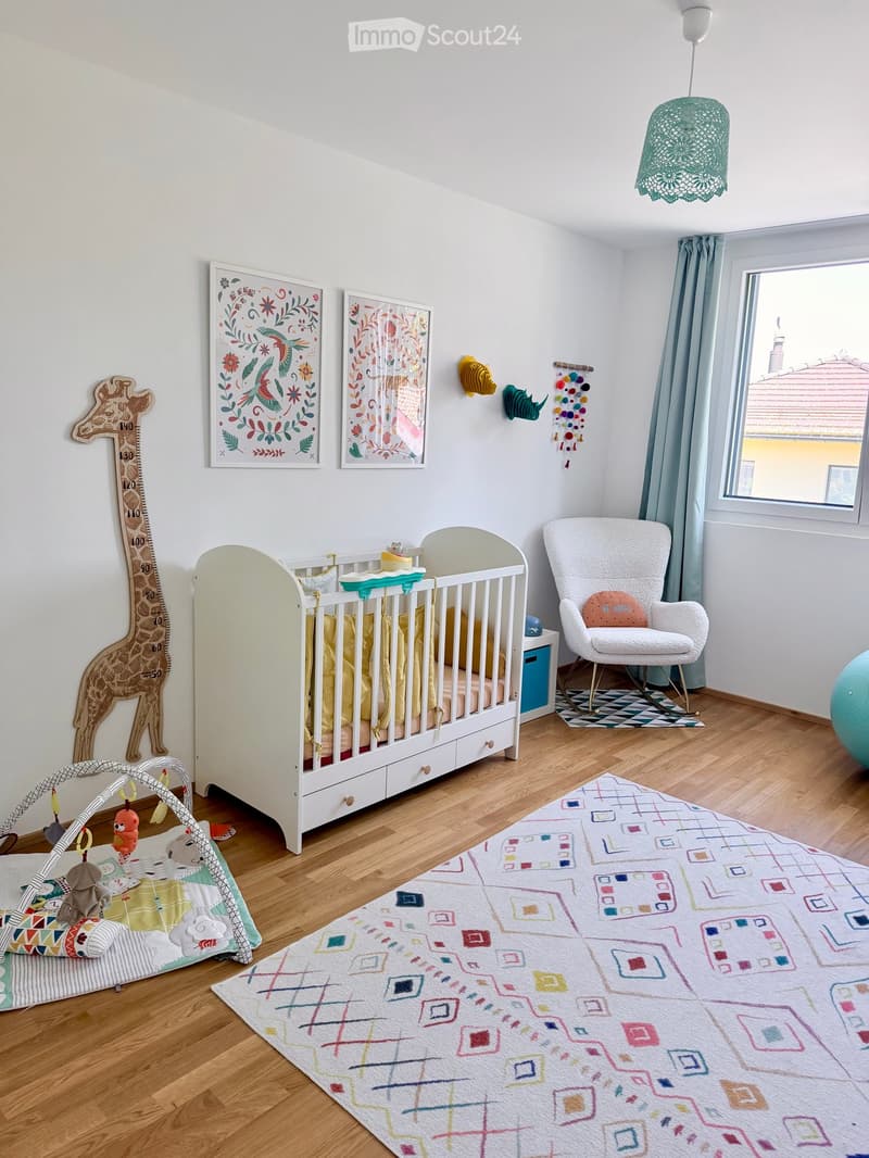 A well-lit, modern nursery with a white crib, a rocking chair, a colorful rug, and various toys and decorations.