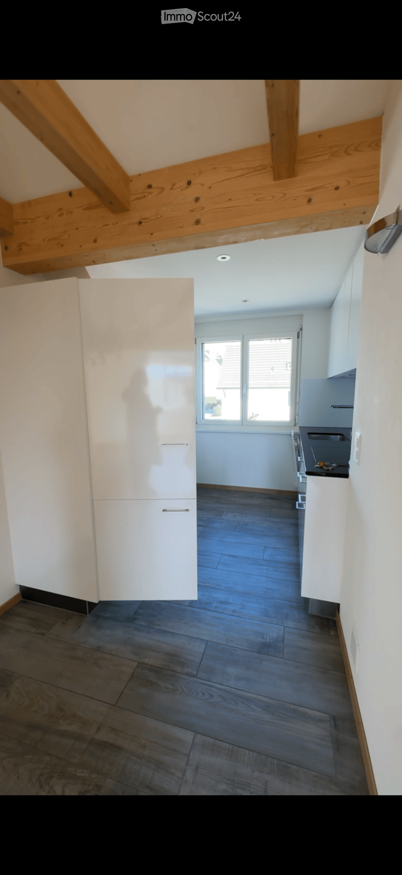 Empty room with wooden flooring, white walls, and a window with blinds. No furniture or equipment present.